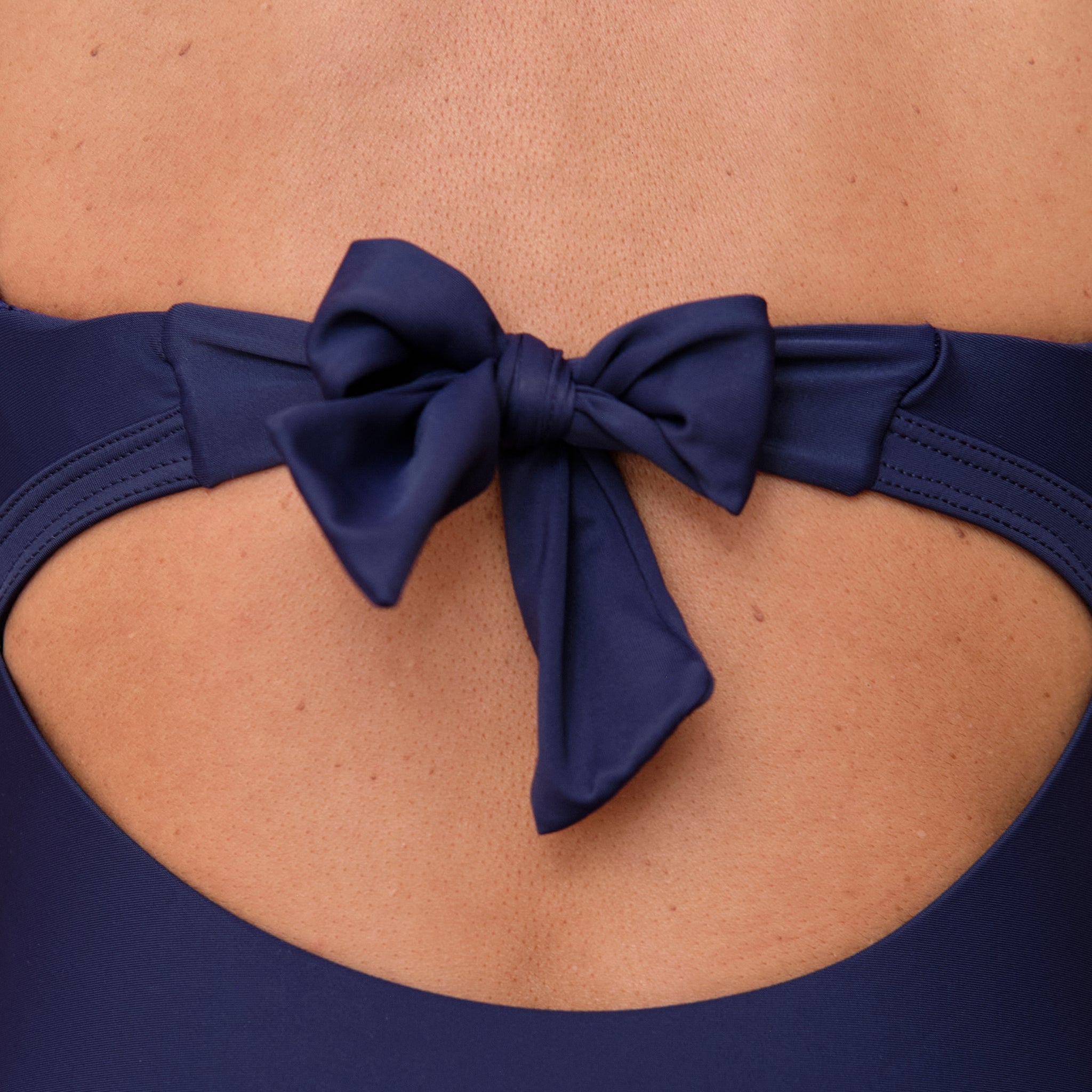 Navy blue swimsuit with a bow detail on a woman's back