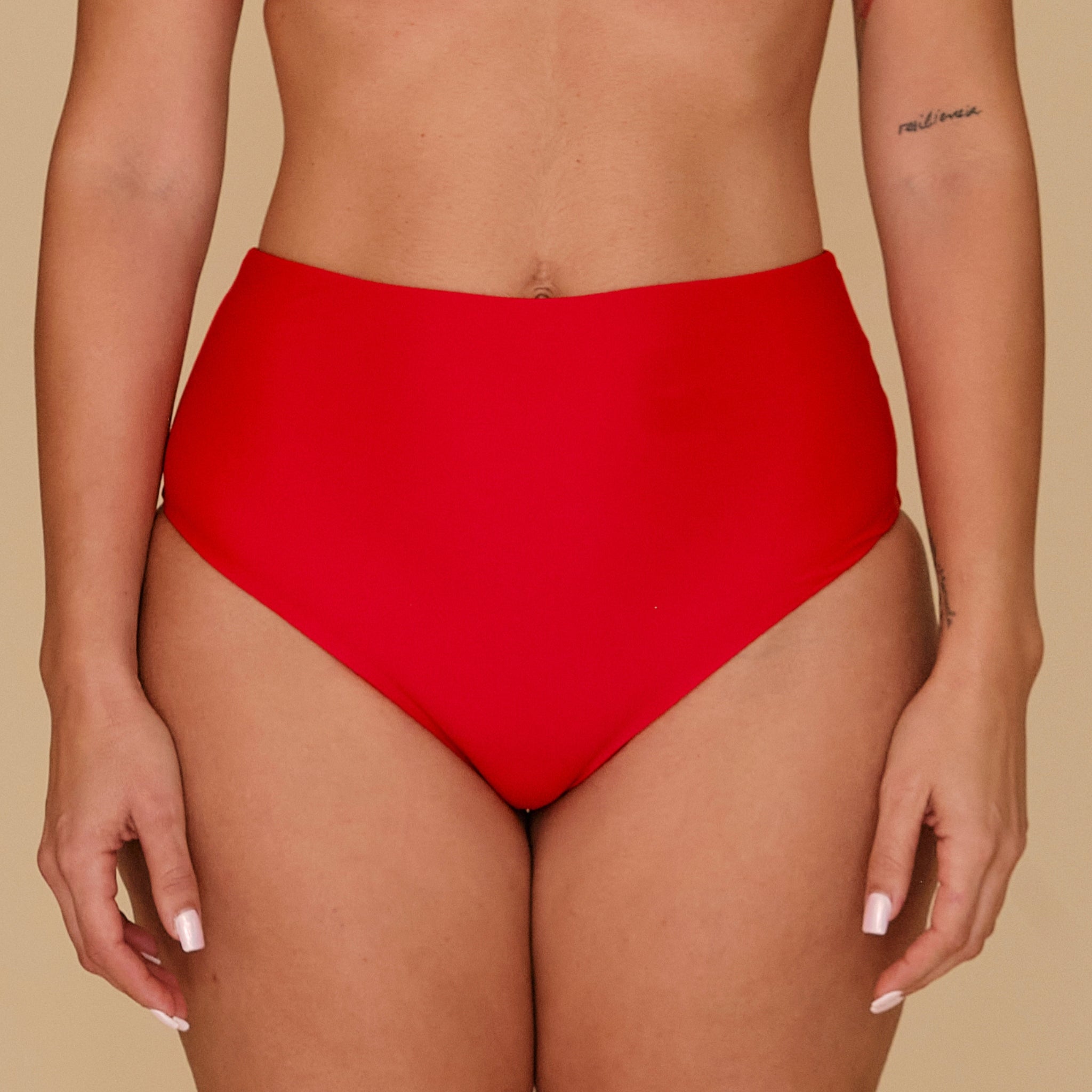 Red high-waisted bikini bottom on a beige background